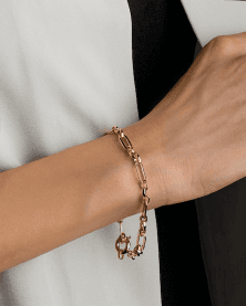 Wrist layered with a gold chain bracelet